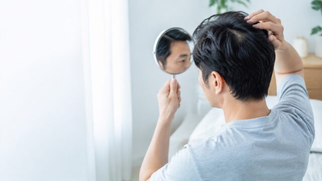 鏡で髪の状態を落ち着いて確認する日本人男性